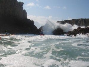 Adaptive paddling.sea kayak adventure in large swell near rocks